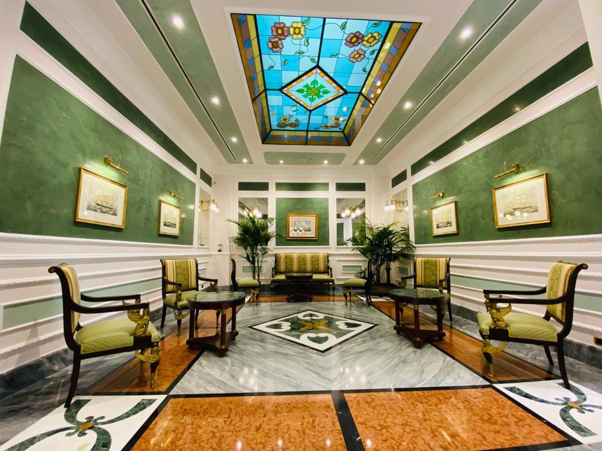 Hotel Bristol Palace Генуя Экстерьер фото The photo shows a well-decorated interior space, likely a lobby or reception area. The walls are painted a soft green, and the ceiling features a colorful stained glass design with geometric patterns. 

There are several elegant furnishings, includin
