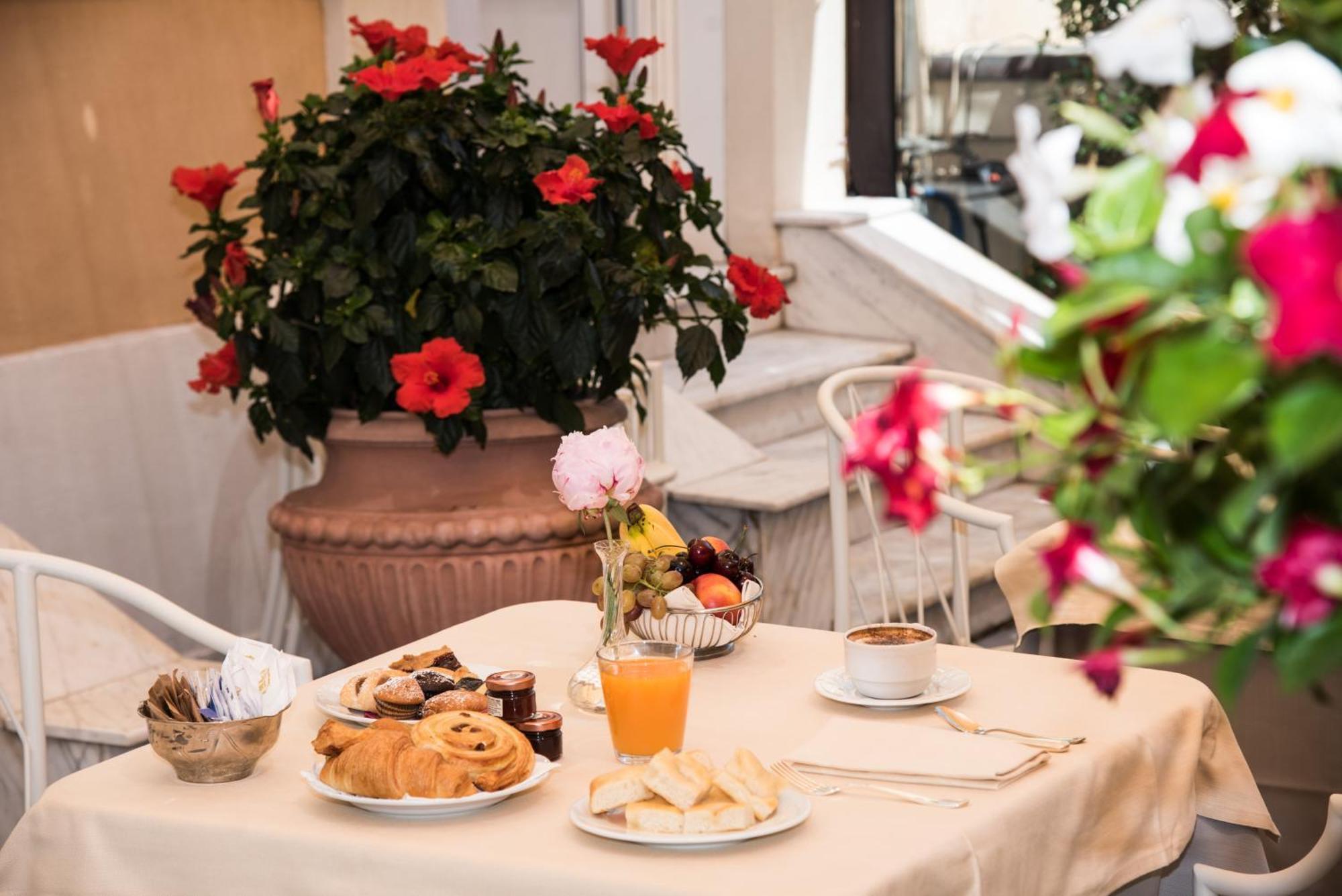 Hotel Bristol Palace Генуя Экстерьер фото The photo shows a charming breakfast setup on a table covered with a light-colored tablecloth. There is a variety of food items, including pastry items like croissants and sweet rolls, alongside some fruit. Also visible is a small glass of orange jui